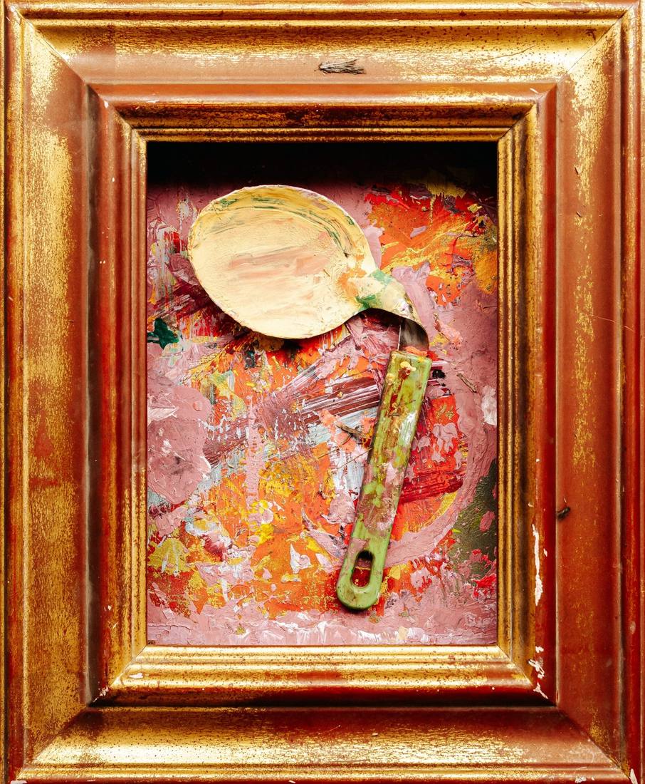 Deep gilt frame holding a pink and orange palette with a paint-caked spoon and a green handle laid across it.