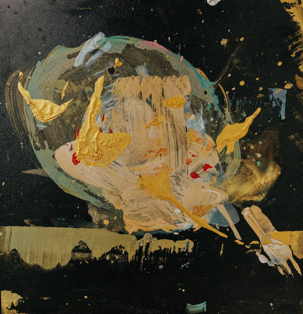 Black board with a round swirl of gold, pale green and cream paint, gold drops around it, a gold hand at lower right.