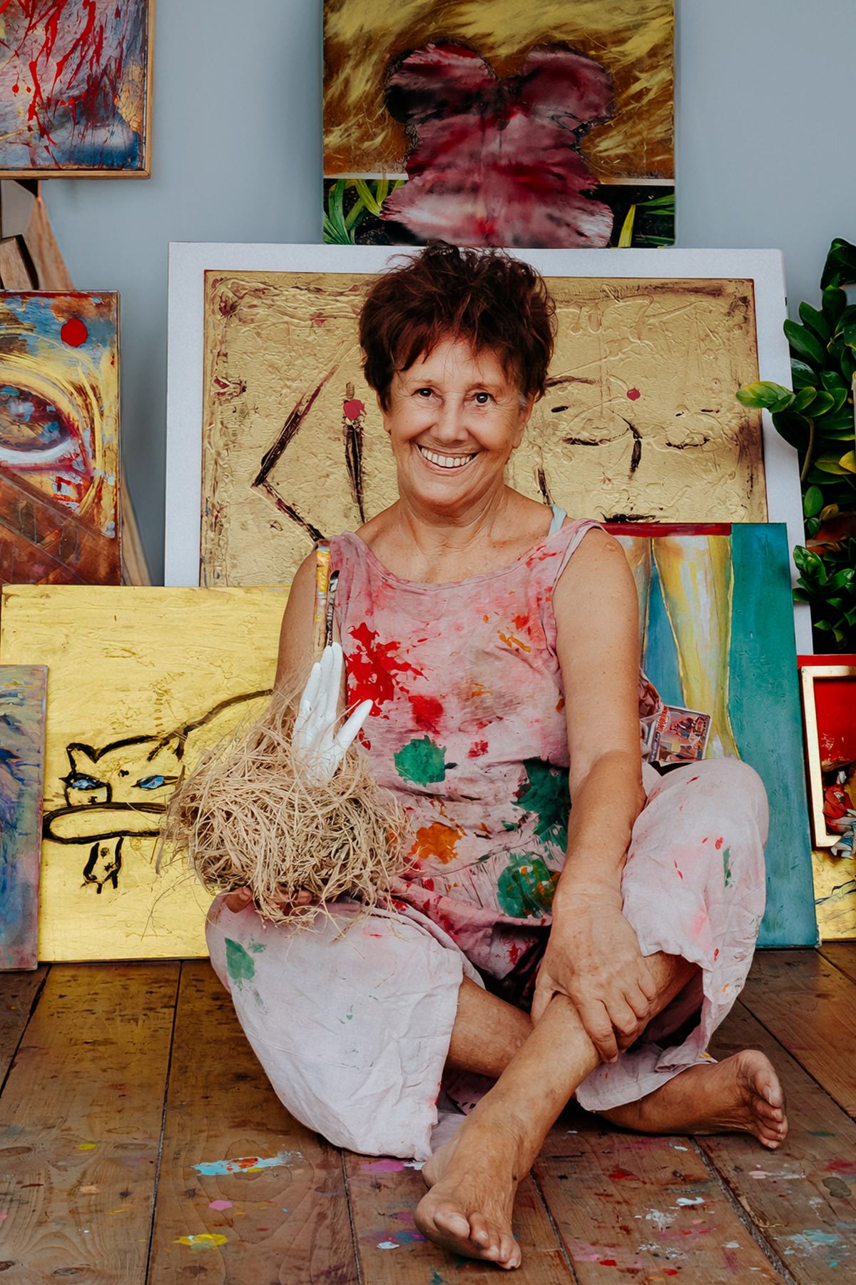 Nana Bors seated on her studio floor holding a raffia sculpture